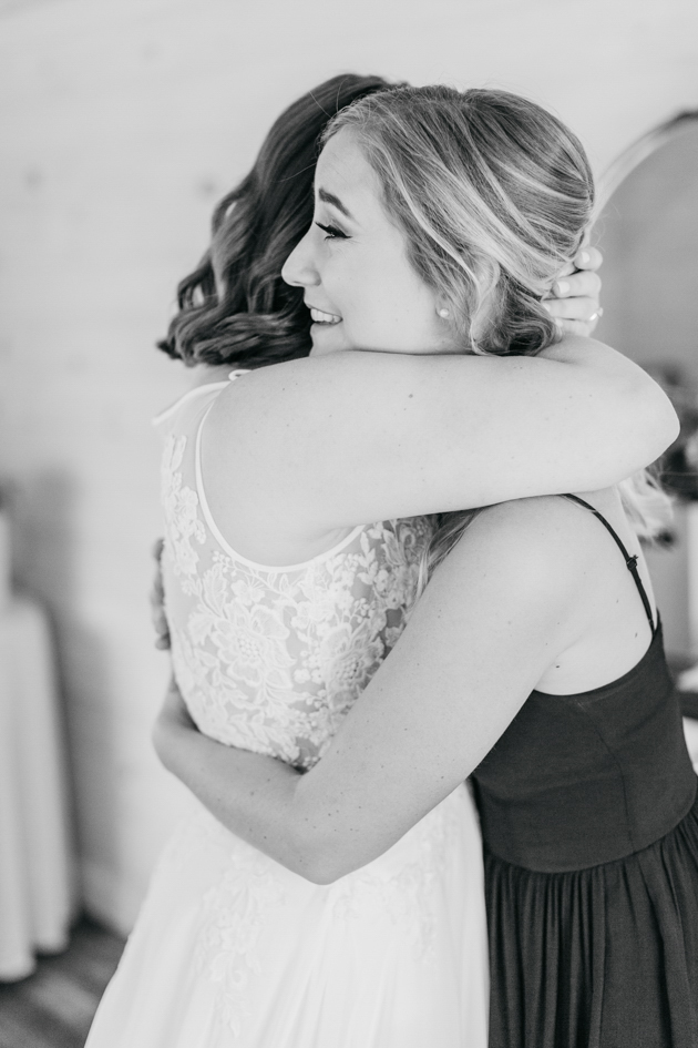 Bride and bridesmaid hugging at Stonewall Estates