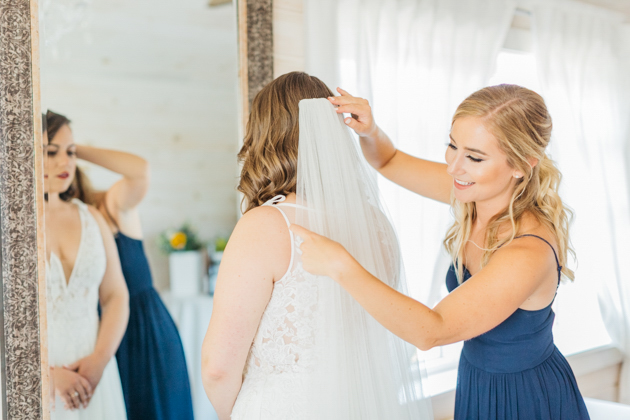 Bridesmaid putting veil on bride at Stonewall Estates