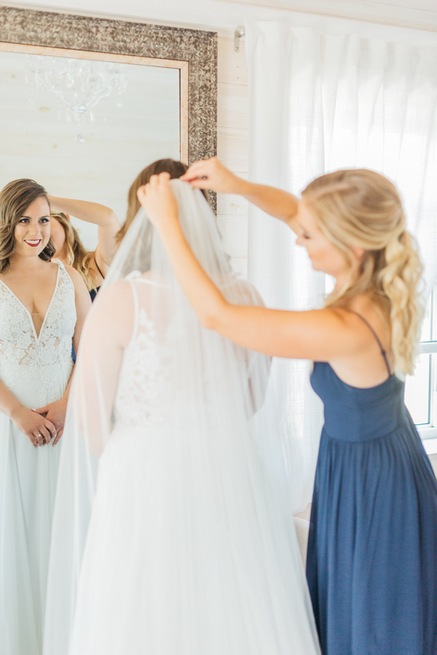 Bridesmaid putting veil on bride at Stonewall Estates
