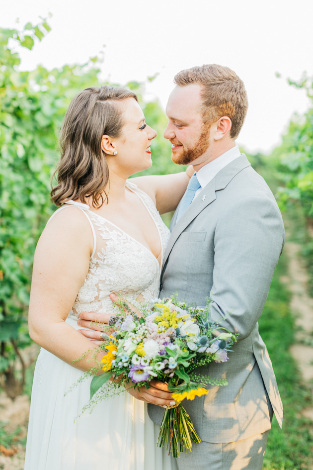 Bride and groom cuddling in vineyard at Stonewall Estates